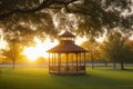 A peaceful park scene with a gazebo and trees in silhouette against the setting sun.