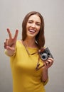 Peaceful photographer. Studio portrait of an attractive young female photographer posing with her camera against a grey Royalty Free Stock Photo