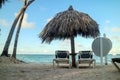Peaceful place with palm trees and cabanas with chairs over white sand beach Royalty Free Stock Photo