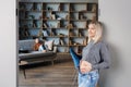 Peaceful pregnant woman touching her belly in modern interior of room and her older child sitting on couch and looking to mother. Royalty Free Stock Photo