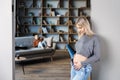 Peaceful pregnant woman touching her belly in modern interior of room and her older child sitting on couch and looking to mother. Royalty Free Stock Photo