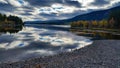 Peaceful and quiet untouched landscape scenery of pebble beach and lake with dramatic clouds reflected in the calm water Royalty Free Stock Photo