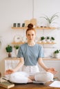 Peaceful redhead young woman is meditating while sitting on desk at home office Royalty Free Stock Photo