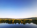 Peaceful river landscape during sunset with strong reflections of nature in water`s surface. Clear sky Royalty Free Stock Photo