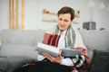 Peaceful satisfied mature woman wrapped warm blanket reading book, favorite literature and drinking tea or coffee, happy Royalty Free Stock Photo
