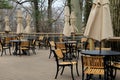 Peaceful scene of tables and chairs with tied umbrellas on outdoor restaurant patio