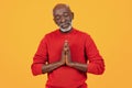 Peaceful senior black man with eyes closed in meditation, hands pressed together in a prayer gesture