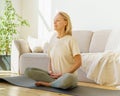 Retired woman meditating and practicing yoga while sitting in lotus pose on floor at home Royalty Free Stock Photo