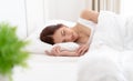 Peaceful serene beautiful young Asian woman wear pajamas lying relaxing sleeping in cozy white bed and keeping eyes closed while Royalty Free Stock Photo