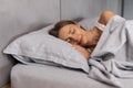 Peaceful young woman wear pajamas lying asleep relaxing sleeping in cozy white bed on soft pillow resting covered with blanket Royalty Free Stock Photo