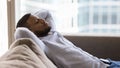 Peaceful sleepy handsome Black guy relaxing on soft couch