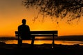 Peaceful solitude, Silhouette of man on bench embraces tranquil sunset