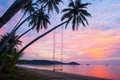 Peaceful time, beautiful clouds and sunset sky. Swing and coconut trees foreground, bay and yacht background. Summer season.