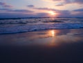 Peaceful view of a cloudy sunset on sandy beach with beautiful reflections on the wet sand