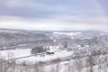 Peaceful winter scene with a red barn in the middle of a snowy hilly field Royalty Free Stock Photo