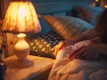 A peaceful woman lies in bed, gently turning off a soft lamp light beside her Royalty Free Stock Photo