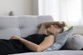 Peaceful woman lying on back on sofa with closed eyes