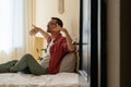 Peaceful young man sitting with closed eyes on bed listening music, relaxing body and mind Royalty Free Stock Photo