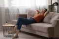 Peaceful young woman relaxing on comfortable couch at home