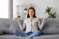 Peaceful young woman sitting in lotus pose on sofa, meditating at home Royalty Free Stock Photo