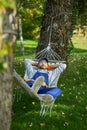 Peaceful young workman wearing uniform taking a break, lying in a hammock outdoors with eyes closed on a sunny day Royalty Free Stock Photo