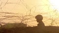 A peacekeeper soldier in a helmet and with a machine gun guarding a checkpoint in the desert, fences and barbed wire, sunrise, sil