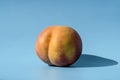 Peach on a blue background as a female body shape like buttocks, thighs, pelvis, pubis. Metaphor of sex, sexuality