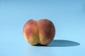 Peach on a blue background as a female body shape like buttocks, thighs, pelvis, pubis. Metaphor of sex, sexuality