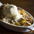 Peach cobbler with French vanilla ice cream in a small single serving dish.