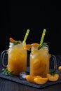 Peach cocktail or tea with ice and mint on a black background Royalty Free Stock Photo