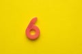 Peach colored number 6 - plastic piece on yellow foamy background