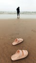 The peach-colored slippers were left on the beach for a while by his parents because he wanted to play in the water Royalty Free Stock Photo