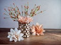 Peach dahlia flower blooms with a hammered metal vase filled with orange colored flower buds sitting on a striped wooden surface