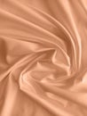 Peach fuzz is the color of the year 2024. Silk fabric folded with beautiful curves with shadows, top view. Royalty Free Stock Photo