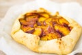 Peach galette on parchment, rustic wooden background. Homemade tart open pie with fresh fruits Royalty Free Stock Photo