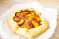 Peach galette on parchment, rustic wooden background. Homemade tart open pie with fresh fruits Royalty Free Stock Photo