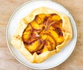 Peach galette on plate on rustic wooden background. Homemade tart open pie with fresh organic fruits Royalty Free Stock Photo