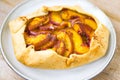 Peach galette on plate on rustic wooden background. Homemade tart open pie with fresh organic fruits Royalty Free Stock Photo