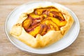 Peach galette on plate on rustic wooden background. Homemade tart open pie with fresh organic fruits Royalty Free Stock Photo