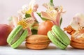 Peach, green macaroon cookies with yellow Alstroemeria flowers, fresh apricots on a beige