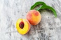 Peach and half peach with leaf on gray concrete background. Fresh sweet peach with pitted. Top view fresh organic peach fruit Royalty Free Stock Photo