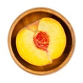 Peach half, cross section of a ripe fruit, in a wooden bowl