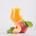 Peach juice in elegance glass with juicy piece peaches on light white wood table, closeup, square.