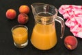 Peach juice in a jug and a glass on a black background. Top view. Royalty Free Stock Photo