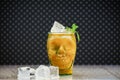 Peach juice in a skull-shaped glass at a marble board with pieces of ice on a spotted background. Fresh peach juice, ice