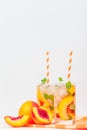 Peach lemonade with ice and mint leaves. Homemade lemonade of ripe nectarine with white and orange ripe. Two glasses of peach tea. Royalty Free Stock Photo