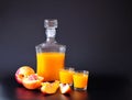 Peach liqueur, glass bottle and two glasses with a light alcoholic drink on a black background Royalty Free Stock Photo