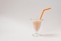 Milk cocktail in a glass glass with an orange tube on a white gray background Royalty Free Stock Photo