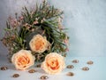 3 peach rose flower blooms with a pink peach wreath and orange brown marbles against a white and plaster background.  Simple, soft Royalty Free Stock Photo