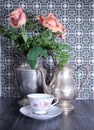 peach roses in an antique silver pewter pitcher and tea pitcher, teacup, saucer teatime Royalty Free Stock Photo